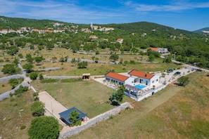 A residential area with a house featuring a swimming pool, surrounded by greenery and stone walls. - Stylish Villa in Lovrec With Sauna for 10 (Lovreć)