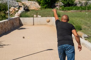 A person playing a game of bowls on a flat, open area with a stone wall and greenery in the background. - Stylish Villa in Lovrec With Sauna for 10 (Lovreć)