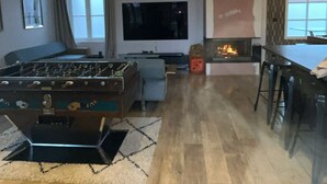 A living room with a foosball table, a flat-screen TV, a fireplace, and a dining area with bar stools. - Large apartment with fireplace (Villers-Cotterêts)