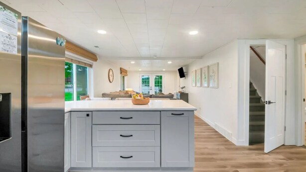 Une cuisine moderne dotée d’un îlot central, de meubles blancs et d’un réfrigérateur en acier inoxydable.