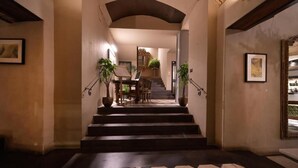 Un escalier menant à une salle à manger avec une table et des chaises, le tout agrémenté de plantes en pot.