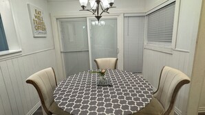 A dining area with a round table, four chairs, a chandelier, and a wall-mounted sign. - Economical & Gorgeous 2-bedroom townhome – Peaceful, Safe & Near the Lake (Garland)