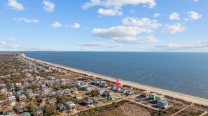 A coastal residential area with houses near the beach and a pier extending into the water. - Almost Heaven - Oceanfront 5BR 3BA home footsteps from beach (Oak Island)