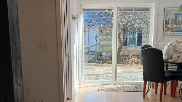 Une pièce spacieuse avec un plancher en bois, un tapis à rayures, une chaise noire et une table à manger.