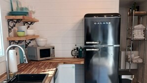 Une cuisine moderne avec un réfrigérateur noir, des plans de travail en bois, un évier et un tapis à motifs.