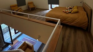 Een slaapkamer met een bed, twee stoelen, een bureau en een raam.