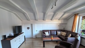 A modern living room with a brown leather sofa, a flat-screen TV, and a wooden coffee table.