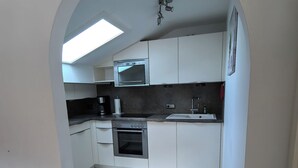 A modern kitchen with white cabinets, a built-in oven, and a skylight.