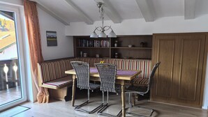 A dining area with a wooden table, striped bench, and metal chairs.
