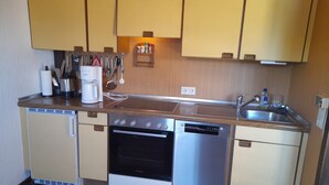 Cocina compacta con horno Bosch, lavavajillas y cafetera en la encimera.