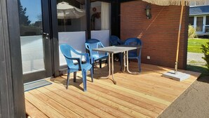 Un patio con una mesa y sillas, una terraza de madera y un muro de ladrillo.