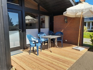 Un patio con tavolo e sedie, un pavimento in legno e un muro in mattoni.