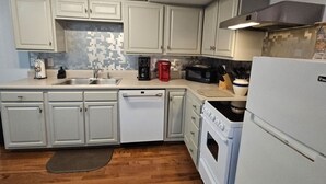 A kitchen with white cabinets, a microwave, a coffee maker, and a refrigerator. - Creekside Delight-Lovely! 20 min to Asheville (Arden)
