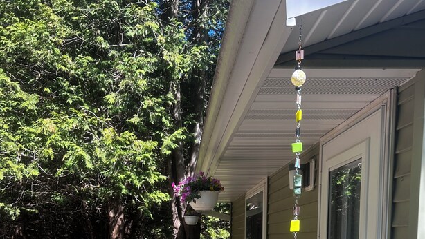Une maison avec un porche couvert, des plantes en pot et un carillon.