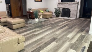 Una sala de estar con una mesa de centro de vidrio, sofás color beige, una chimenea y un televisor montado en la pared.