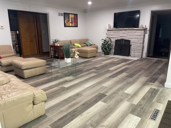 A living room with a glass coffee table, beige sofas, a fireplace, and a TV mounted on the wall. - Peaceful duplex house in Omaha perfect for a relaxing getaway (Omaha)