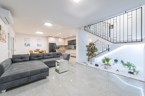 Ein modernes Wohnzimmer mit einem Ecksofa, einem Glastisch und einer Treppe mit Geländer.