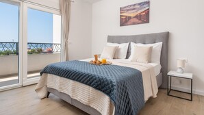 Una camera da letto con un letto, un comodino con una lampada, un quadro appeso e vista panoramica tramite una porta scorrevole.