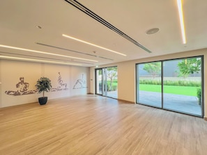 Ein geräumiges Zimmer mit großem Fenster, einer Topfpflanze und Wandbildern.