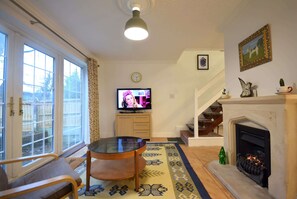 Ein Wohnzimmer mit Kamin, Fernseher und Essbereich.