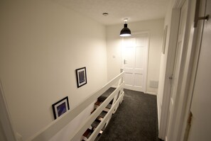 A narrow hallway with a carpeted floor, white walls, and a white door at the end. - Cosy 2BDR House with Driveway Near Manchester (Manchester)