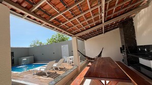 Eine Außenpatio mit Pool, Liegestühlen, einem Holztisch und einer Hängematte.
