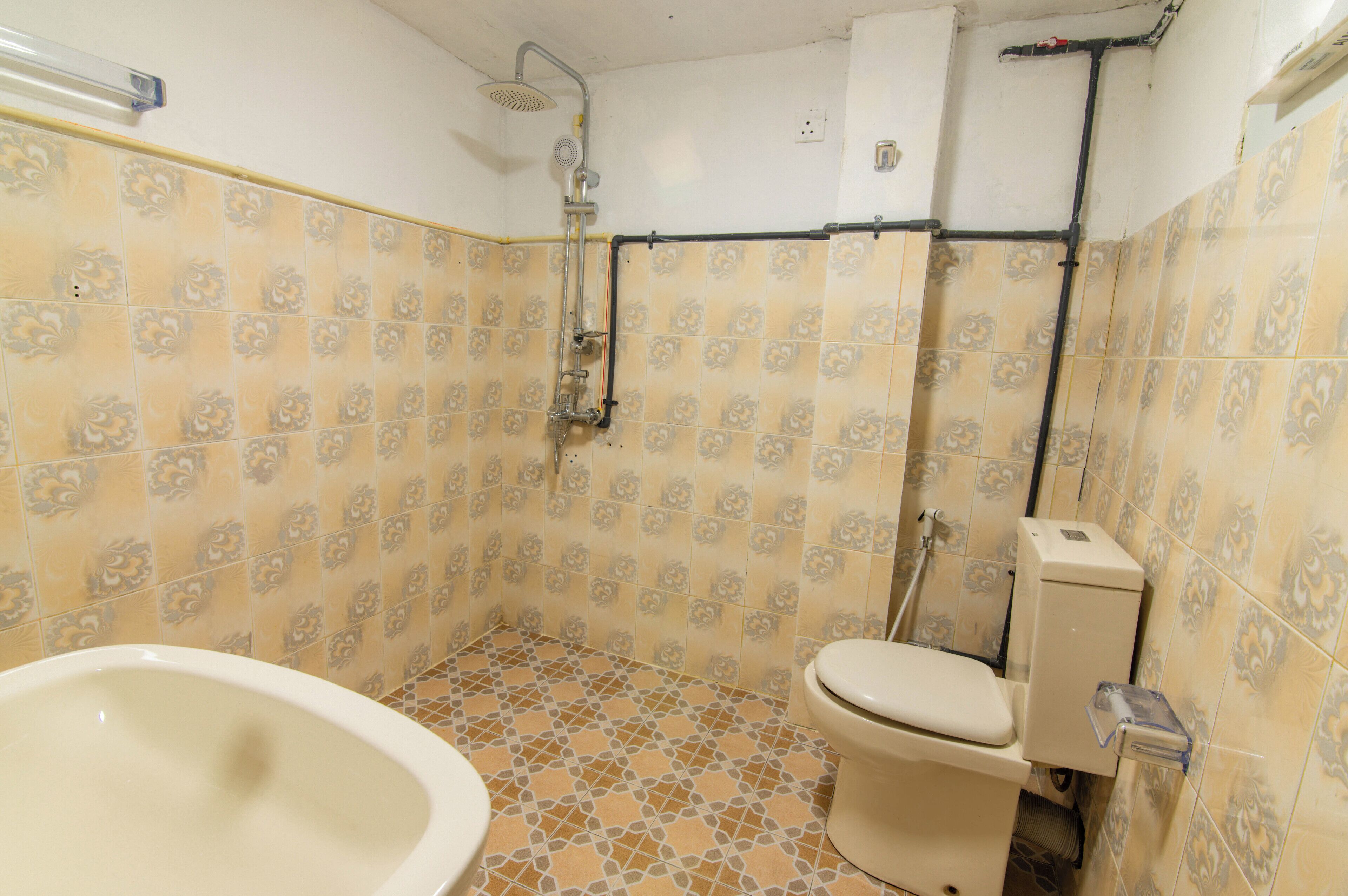 Une salle de bain avec des carreaux décorés, des toilettes, une baignoire et une douche.
