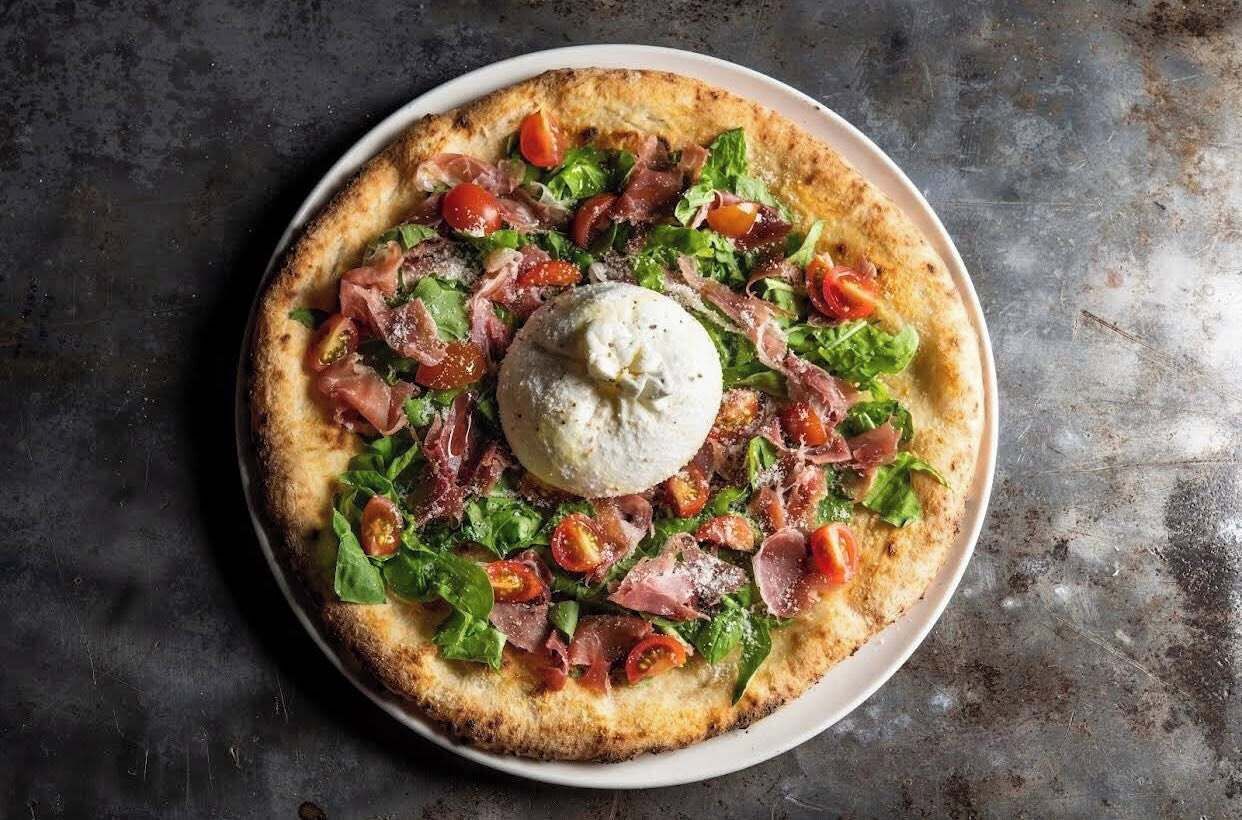 Une pizza garnie de divers ingrédients et surmontée d’une cuillerée de sauce au centre.