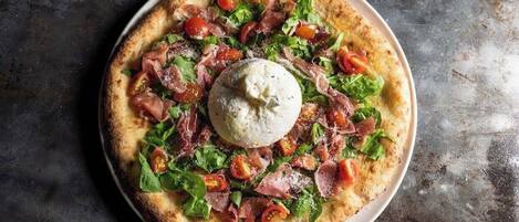 A pizza with toppings and a dollop of sauce in the center.