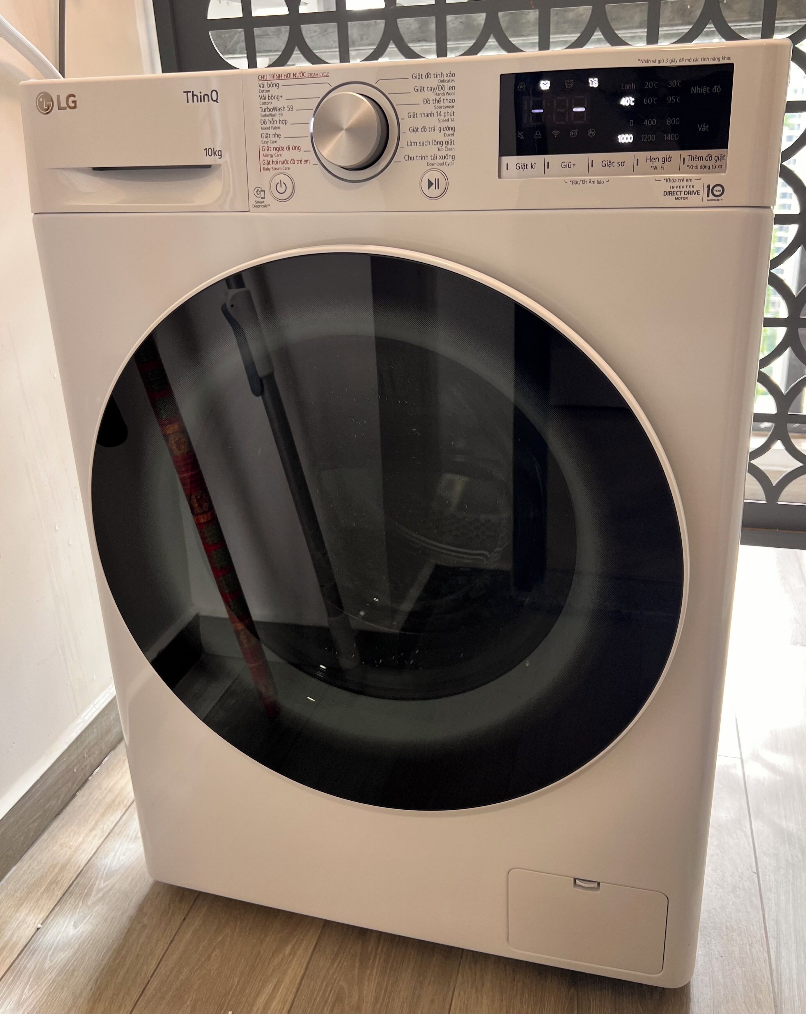 Eine weiße, frontbeladene LG ThinQ Waschmaschine mit Bedienfeld, Digitalanzeige und einer transparenten Tür.