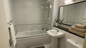 Ein modernes Badezimmer mit einer gläsernen Duschkabine, einer weißen Badewanne und einem Waschbecken mit Spiegel darüber.