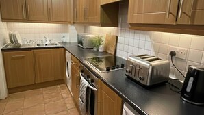 Eine Küche mit Holzausstattung, einer Waschmaschine, einem Toaster und einem Wasserkocher.