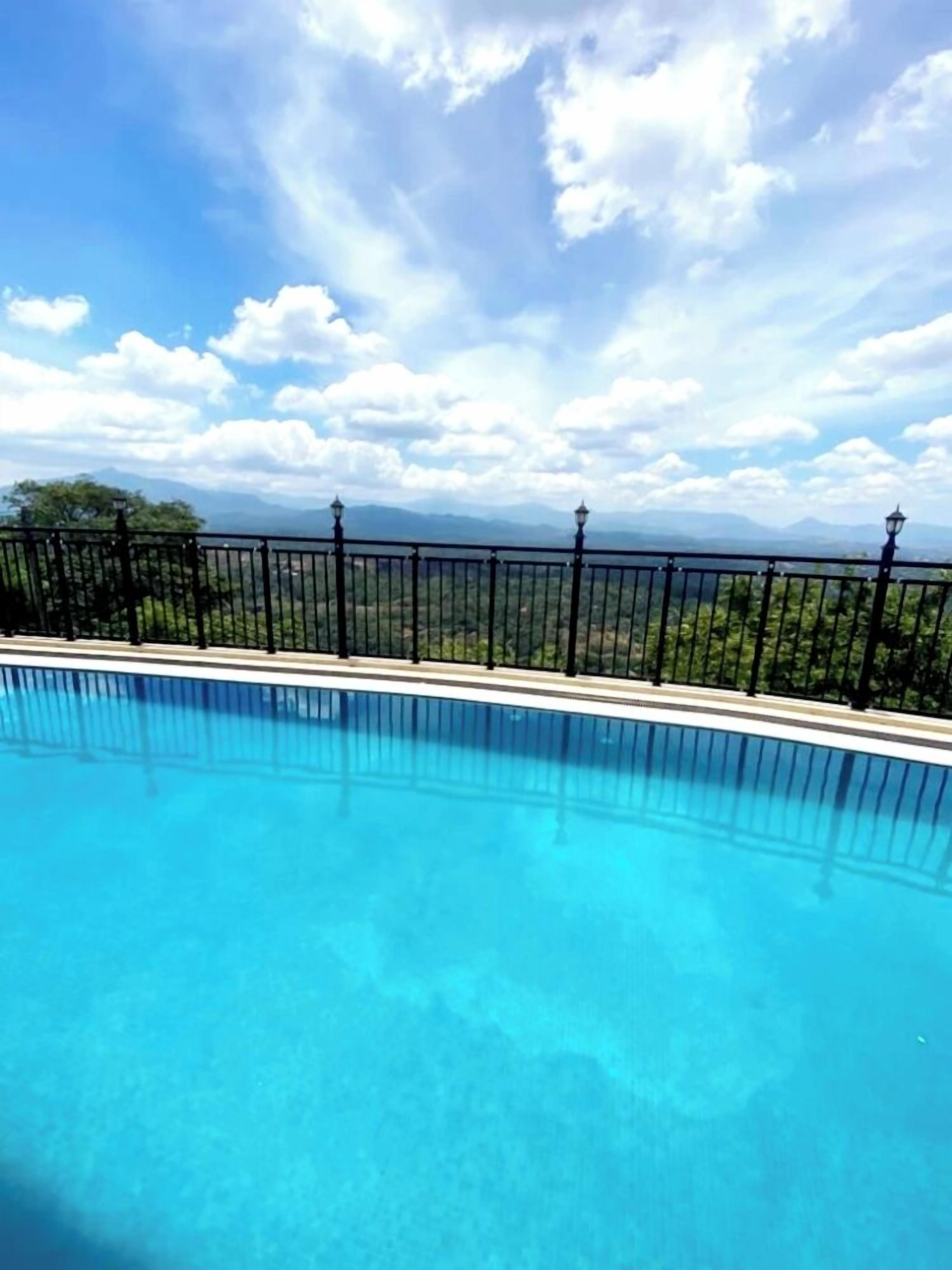 Una piscina al aire libre, sombrillas, sillones reclinables de piscina