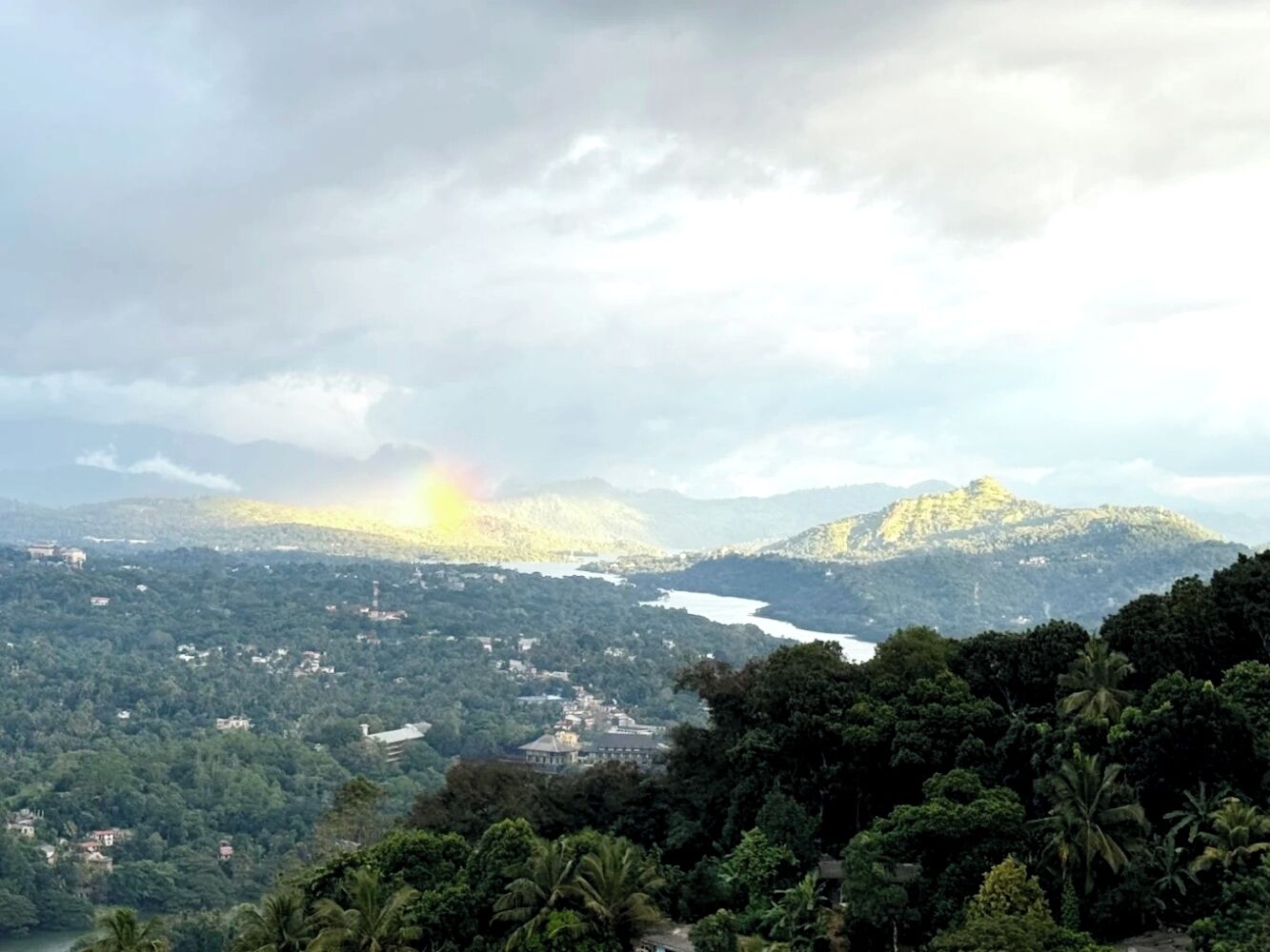 Une vue panoramique d’un paysage montagneux, avec une rivière, un petit village et un bâtiment imposant au centre.