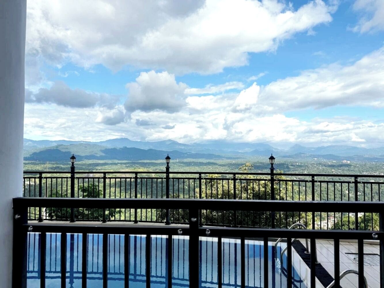 A balcony with a view of mountains and a pool.