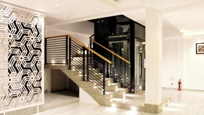 A modern interior with a staircase, a decorative wall panel, and a fire extinguisher. - Hotel Sky Gate Kandy  (Kandy)