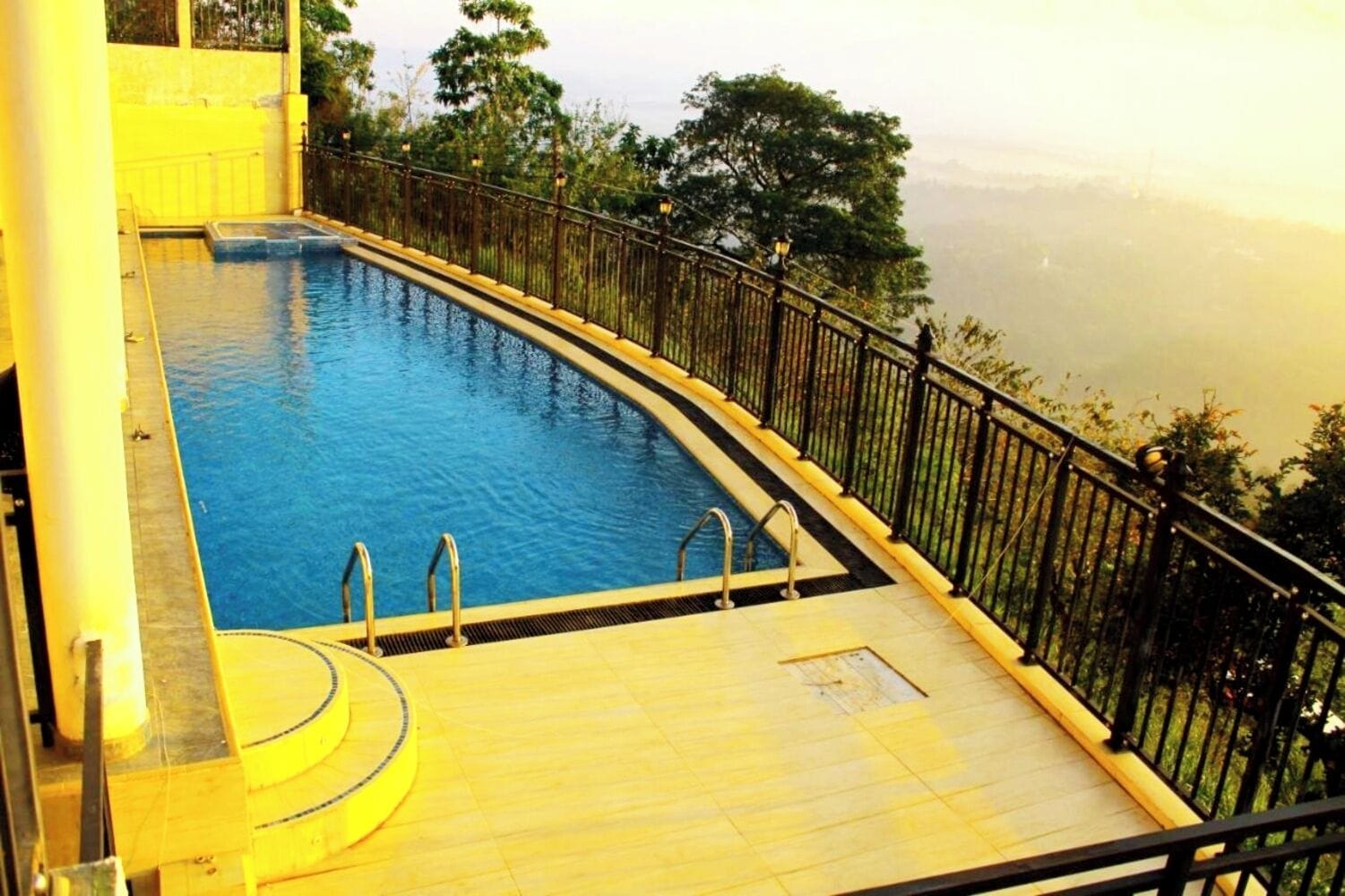 A swimming pool with a curved edge, surrounded by a black metal railing.