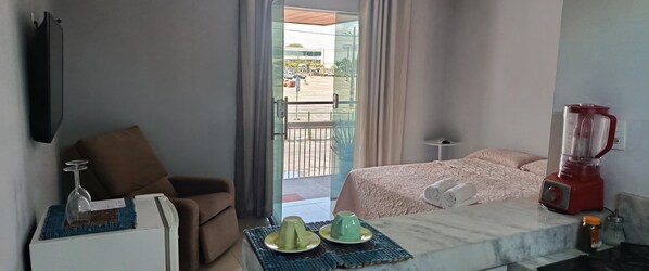 Une chambre d’hôtel avec un lit, une petite table sur laquelle se trouve un mixeur, un téléviseur fixé au mur et une vue sur l’extérieur.