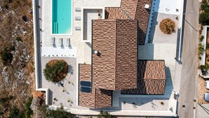 Vue aérienne d’un bâtiment moderne doté d’une piscine, d’un espace extérieur aménagé et d’un revêtement de sol combinant des carreaux et du bois.