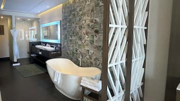 A modern bathroom with a freestanding bathtub, a vanity with a mirror, and a decorative wall with leaf patterns.