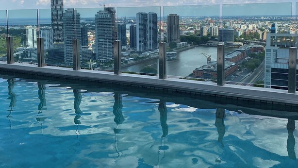 Piscina en la azotea con vistas a un paisaje urbano, que incluye edificios modernos y un río.