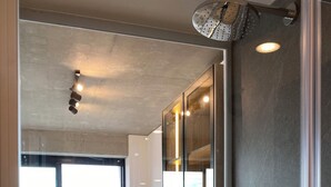 Un dormitorio moderno con una cama grande, cabina de ducha de vidrio y vista a la ciudad.