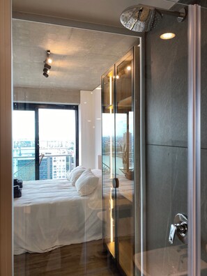 A modern bedroom with a large bed, a glass shower enclosure, and a city view. - Charming studio on the 33rd floor in the best location in Buenos Aires (Buenos Aires)