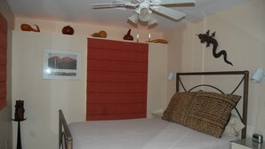 A bedroom with a bed, a ceiling fan, a nightstand, a lamp, and a wall-mounted decoration. - The Casita at Lizard Gate is a 1-bedroom guest house in mid-town Tucson. (Tucson)