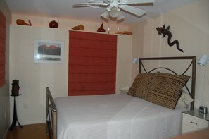 A bedroom with a bed, a ceiling fan, a nightstand, a lamp, and a wall-mounted decoration. - The Casita at Lizard Gate is a 1-bedroom guest house in mid-town Tucson. (Tucson)
