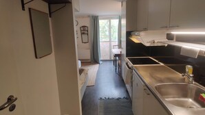 Una cocina compacta con estufa, fregadero y comedor con mesa y sillas.