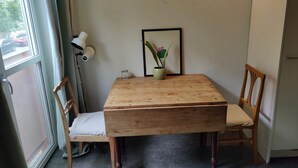 Una habitación con una mesa de madera, dos sillas, una planta en maceta, un cuadro enmarcado y una lámpara.