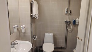 Un baño pequeño y funcional con lavamanos, inodoro y ducha.