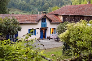 A traditional house with a blue door and windows, surrounded by greenery. - Charming Old Farmhouse in Secluded Nature – Perfect for Family & Friends (Sédeilhac)