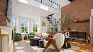 A spacious living room with a modern sofa, a coffee table, and a staircase leading to an upper level.